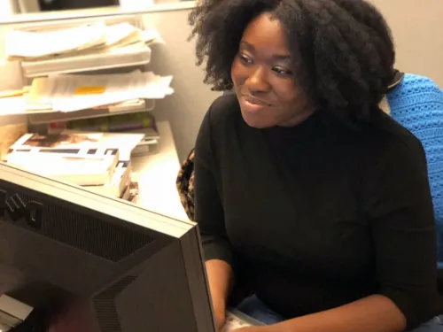 Writing alumna Lashanda Anakwah typing on a computer in an office.