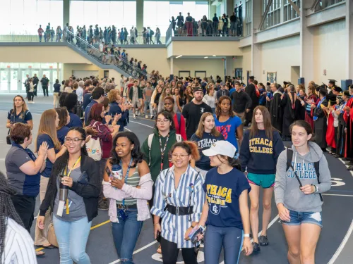 Young people walking on an indoor track with faculty cheering