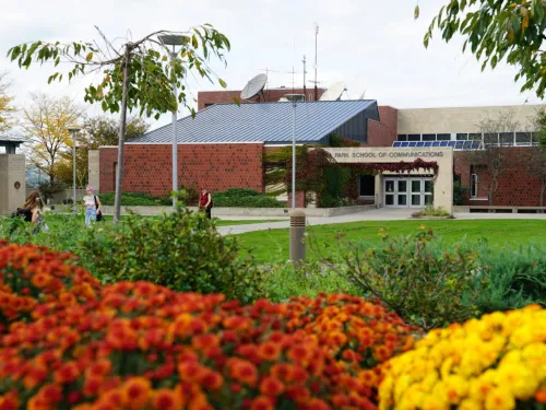 A college building with flowers in the foreground