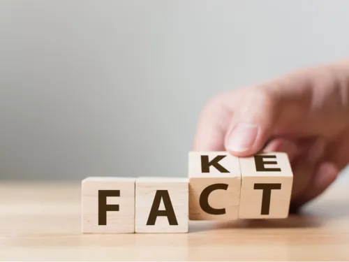 A hand moving lettered blocks spelling FAKE to FACT
