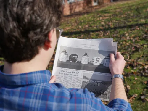 A young man reading a newspaper outside