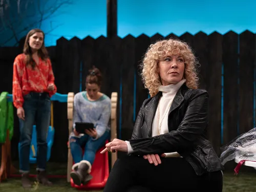 woman sitting in lawn chair in backyard while other women look on