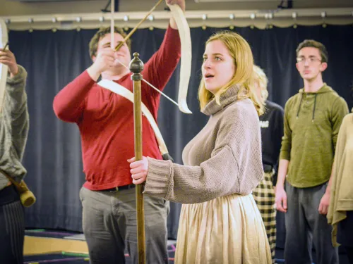 a woman holds a bow and arrow on stage