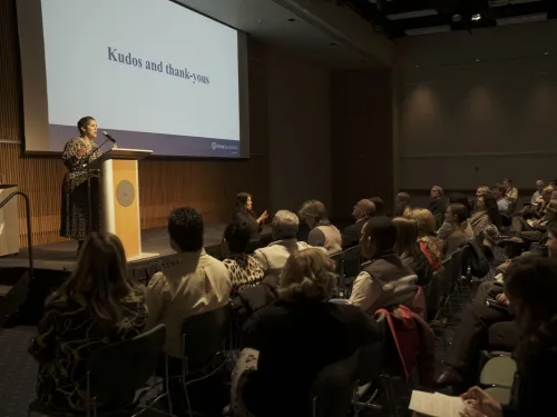 President Collado stands at a lectern on a stage in front of a large audience