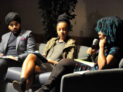 Two students on stage with a guest artist having a deep dialogue