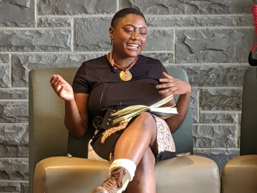 A student activist siting a couch, with a vibrant expression, talking about her activism