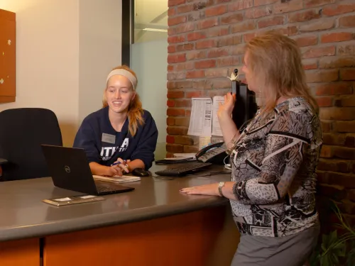 Client standing at the Service Desk receiving help support >>