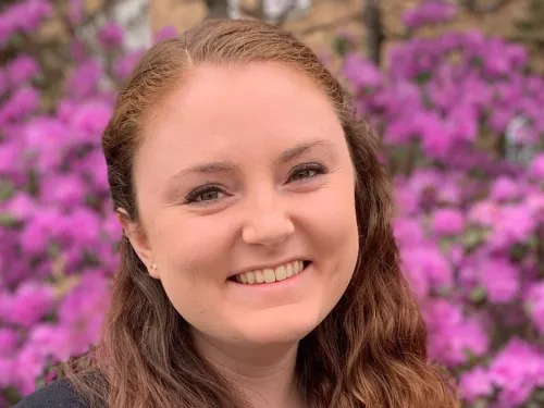 This is a photo of Abby Preston. Abby is wearing a light green shirt with a black sweater. Abby has long brown hair.