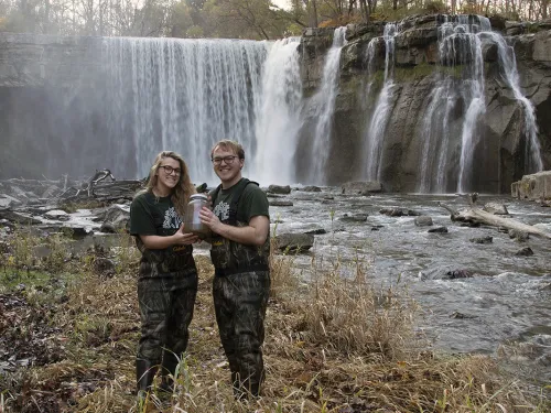 students taking water samples by a waterfall