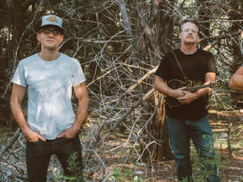 People standing in woods holding instruments