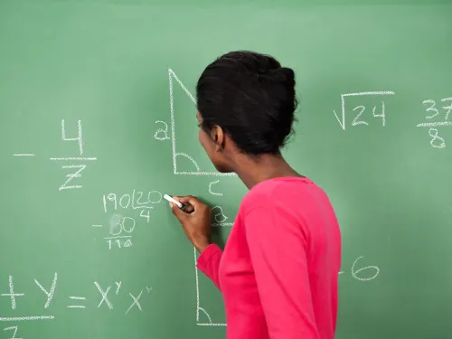 Woman at chalkboard writing a math equation 