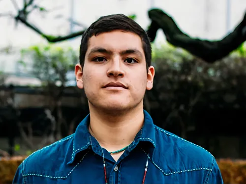 A young man with a straight , relaxed expression looks directly into the camera