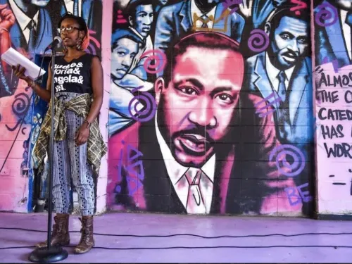 spoken word poet in front of mural