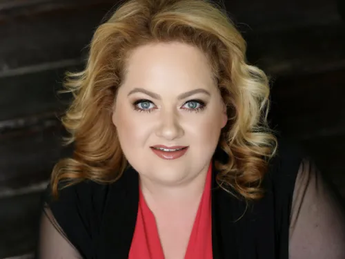 Headshot photo of person smiling in front of dark background