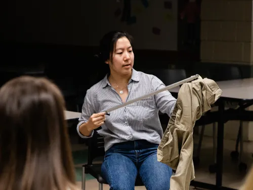 A student is seated and using a grabber to put on pants.