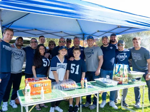 group of alumni under a tent about to tailgate