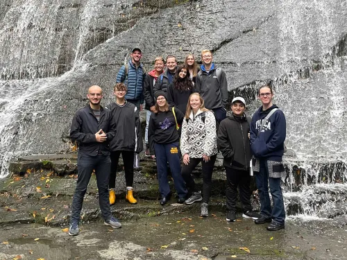Students standing in front of a waterfall