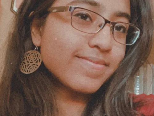Photo of young woman with brown hair wearing glasses. 