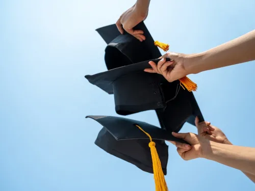 hands holding graduation caps in the air