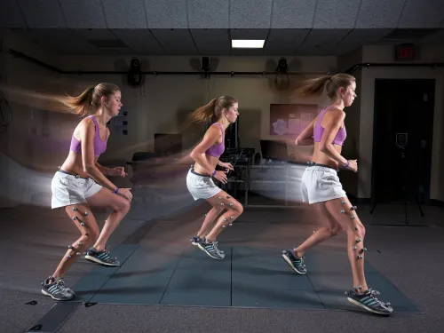 A student is running in slow motion with sensors attached to their legs to track movement.
