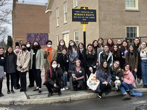 Students in front of a sign marking the location of the first convention for women's right