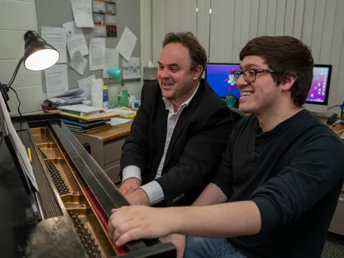 two people sitting at a piano