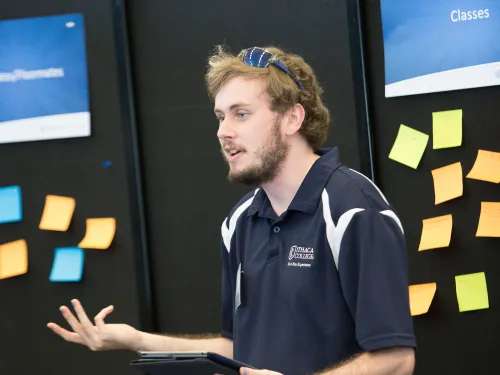 A student is standing up giving a presentation to an audience.