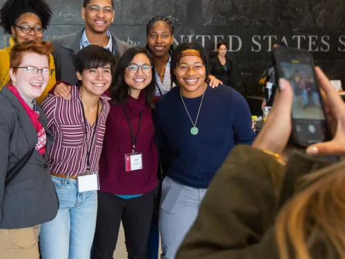 A group of 10 students are smiling to have their picture taken at the US Senate.
