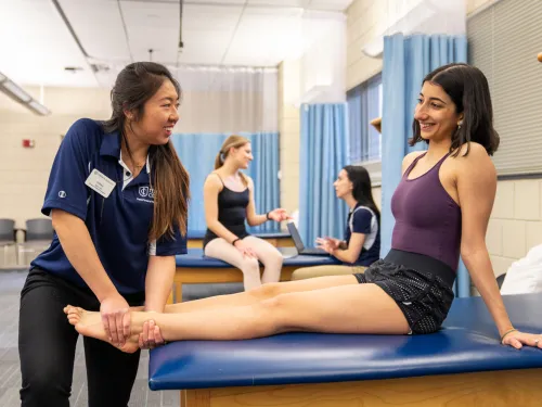 A physical therapy student applying therapy to someone's foot