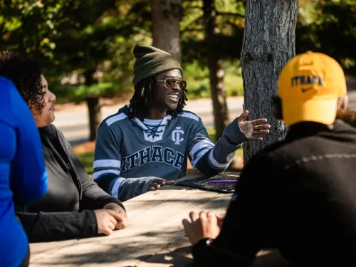 group of students socializing outside at a picnic table