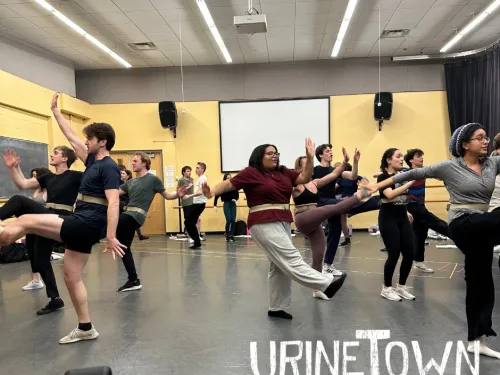 Students swinging their arms and kicking out their legs in a play rehearsal