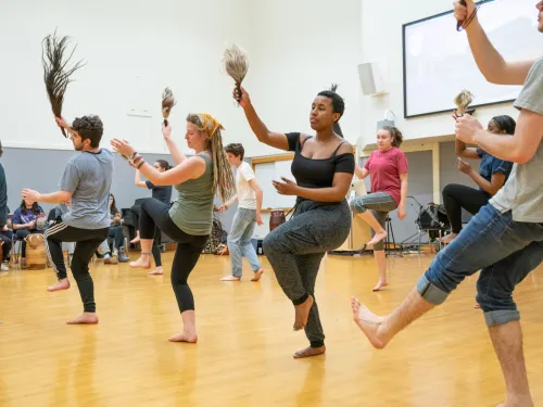 A group of students dances in bare feet.