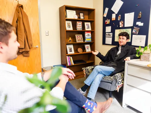 Male advisor sits and talks with a student