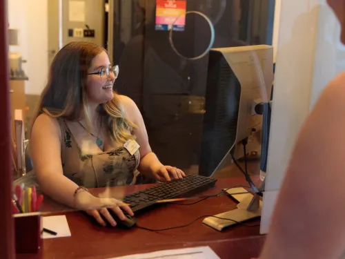 A Theatre Administration student works at the box office on a computer.