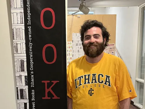 Photo of a man standing by a books sign.