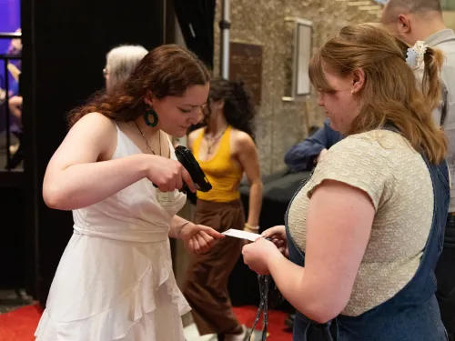 An Theatre Administration student scans the ticket of a patron using a digital ticket scanner.