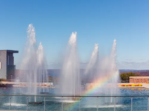 A rainbow appears among six fountains.