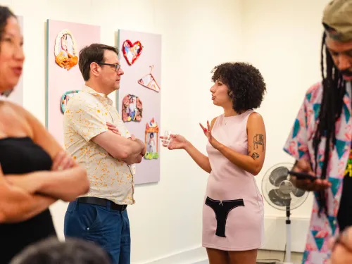 Four people in an art gallery looking at art and having conversations 