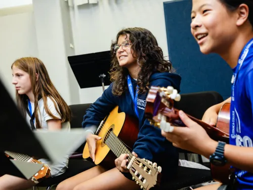 three young students hold guitars