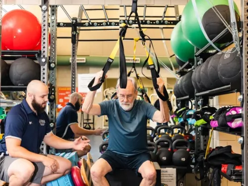 A student is assisting a Wellness Clinic client with strength building.