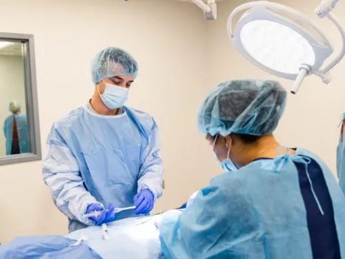 Two students are performing surgery under the guidance of a clinical preceptor.