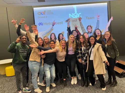 a group of students poses in front of a screen