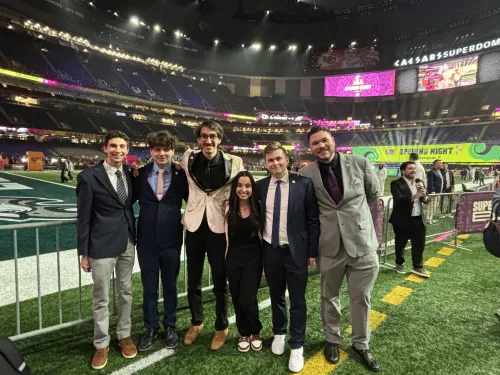 College students in a group photo on an NFL football field.