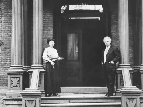 two people stand on the steps of the Ithaca Conservatory of Music building in this black and white historical photo