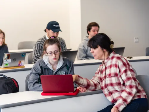 a professor and student look at a computer screen together 