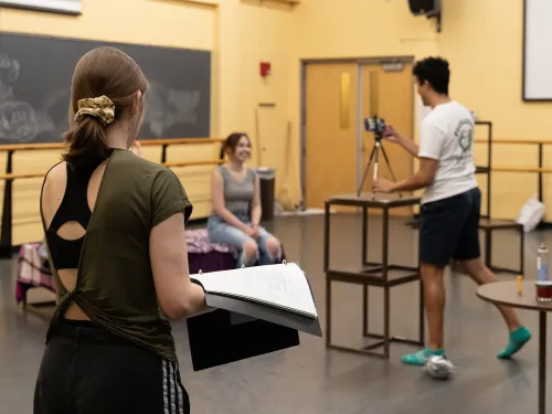 A student directs actors in a studio,