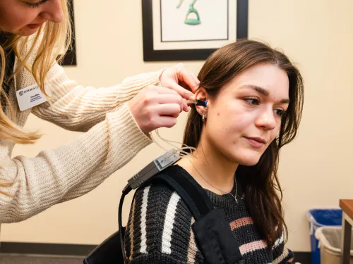 A patient receives a hearing test on her ear.