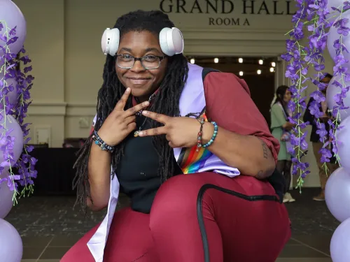 Cefari at Lavender Graduation, squatting and throwing up peace signs