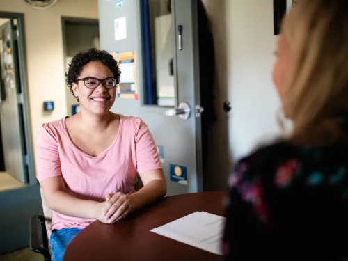 a student sits across the desk from an advisor 