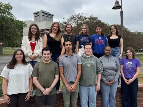 Photo of twelve students posing on campus